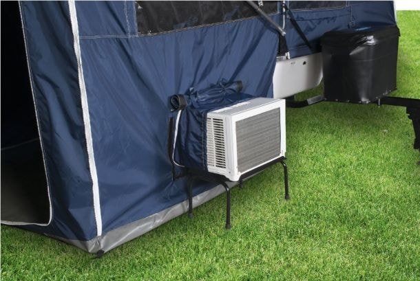 An AC unit attached to a tent that has an AC port on the wall